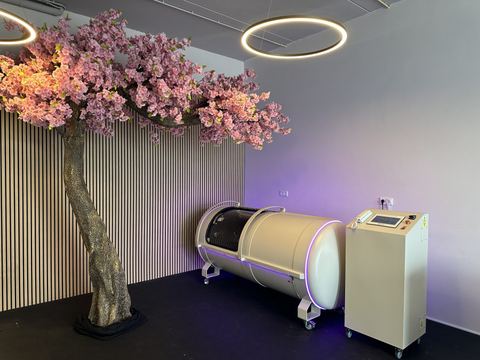 OxyHelp-cabine in een lichte wellnessruimte met een bloeiende boom